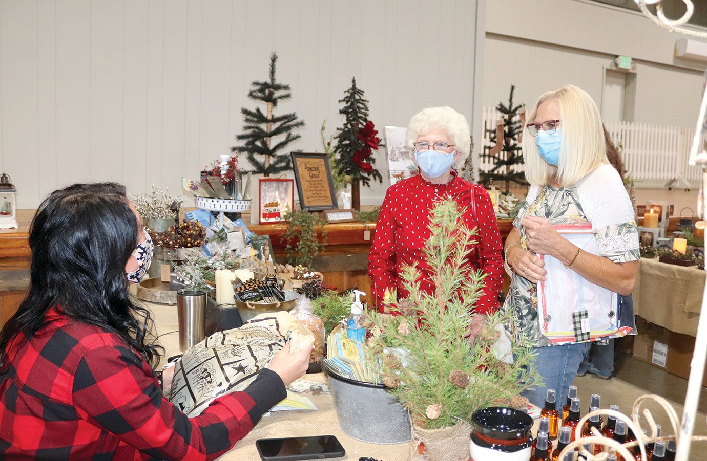 Ashleigh McKinney, from left, helps Donna Barnett and Arlene VanScoyoc with their holiday selections Saturday at the Fairgrounds. McKinney works for Leanne Corbin, owner of Harvest Inn Interior Decor and Gift Shop on the city's south side.